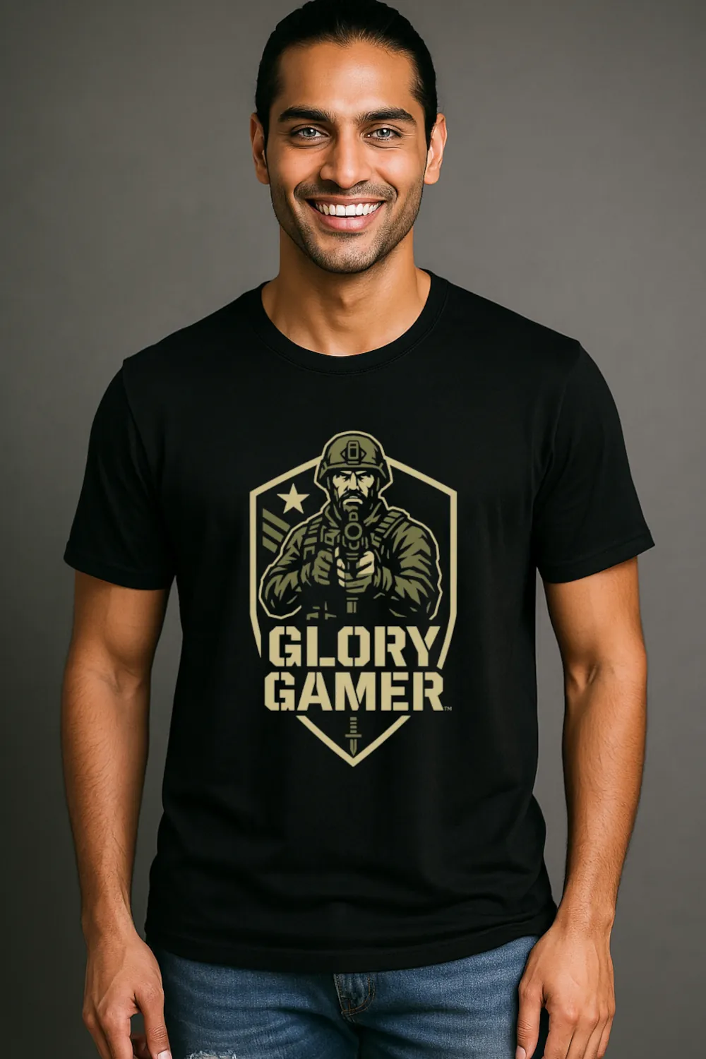 A smiling man wearing a black graphic t-shirt featuring a bold design that reads "GLORY GAMER." The shirt is styled with a modern fit, showcasing a clean and polished look. The background is a neutral gray, emphasizing the shirt's design and the model's confident expression. This image captures the essence of contemporary graphic tee fashion, appealing to men who appreciate stylish and expressive clothing.